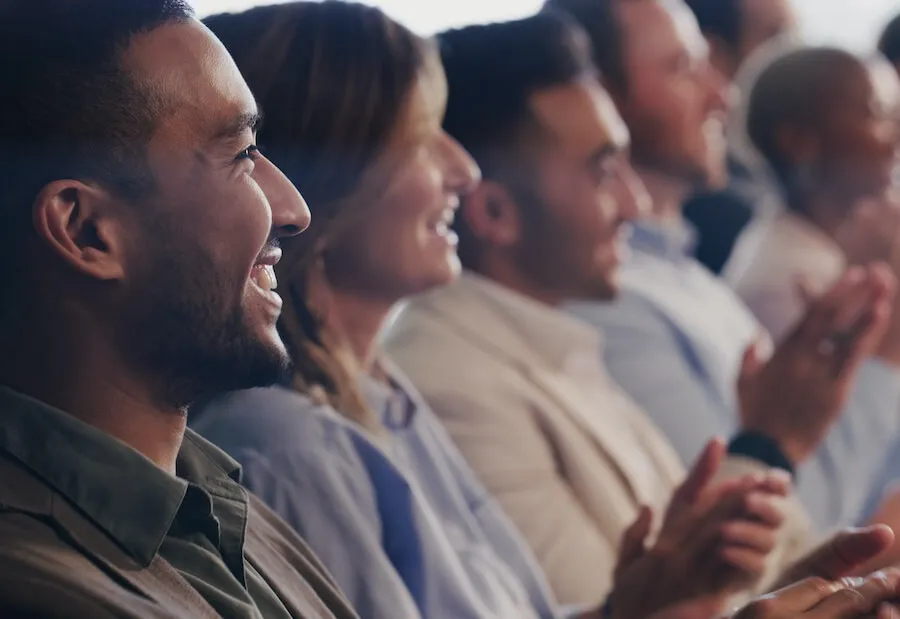 Smiling audience members seated in a row at a talk