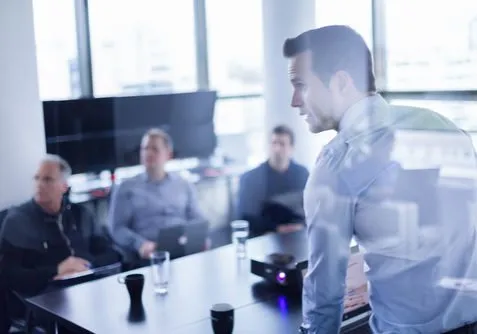 A presenter speaking to colleagues around a meeting table